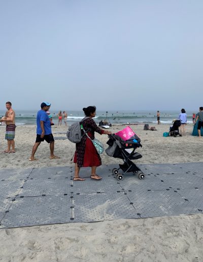 A women at the beach pushes a stroller atop Beach Trax.