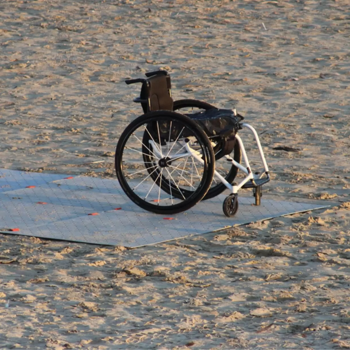 A wheelchair over an access mat on the beach